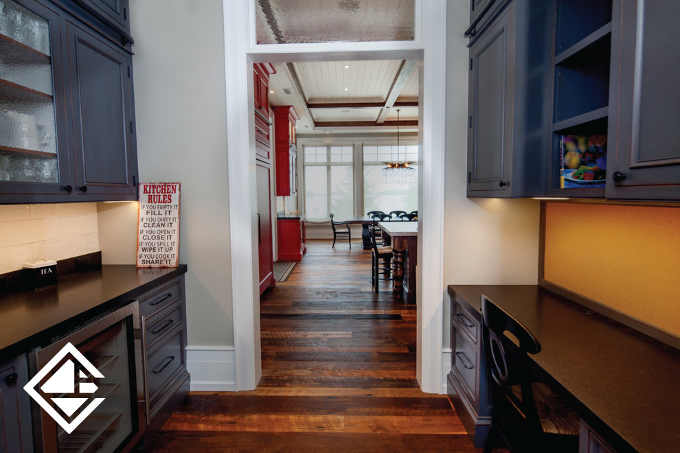 Huge mountain style l-shaped medium tone wood floor eat-in kitchen photo with a farmhouse sink, raised-panel cabinets, granite countertops, white backsplash, stainless steel appliances, an island and gray cabinets