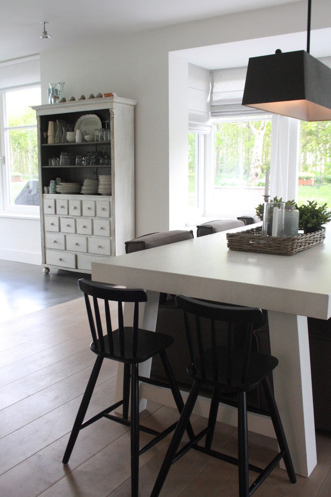 This is an example of a contemporary dining room in Amsterdam with white walls and light hardwood floors.