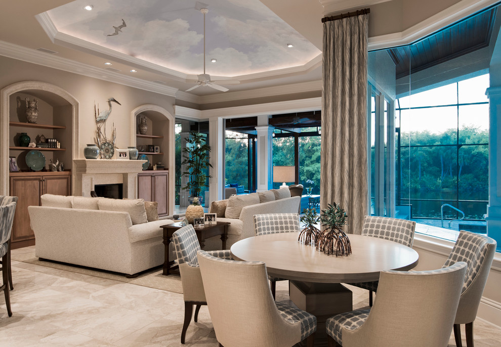 This is an example of a mid-sized transitional open concept family room in Miami with beige walls, travertine floors, a standard fireplace, a concrete fireplace surround and a concealed tv.