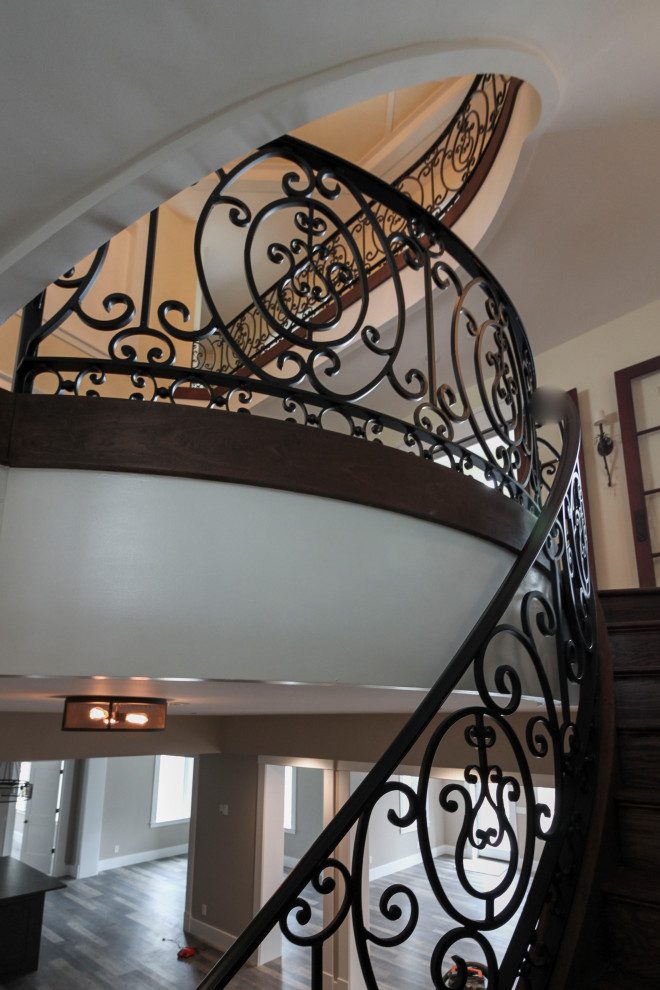 Photo of an expansive transitional wood curved staircase in DC Metro with wood risers and metal railing.