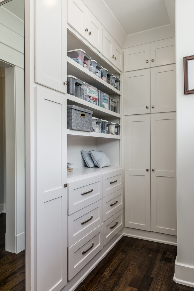 Transitional gender-neutral storage and wardrobe in Nashville with shaker cabinets, white cabinets and dark hardwood floors.
