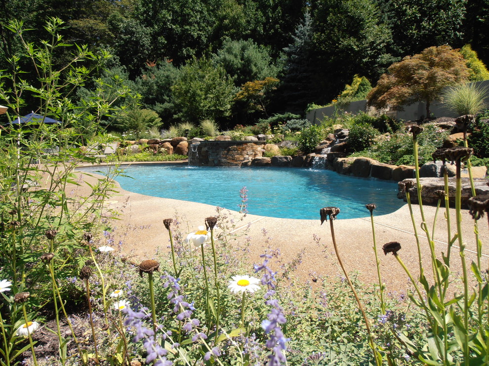 Inspiration for a traditional backyard custom-shaped natural pool in Philadelphia with a water feature and decking.
