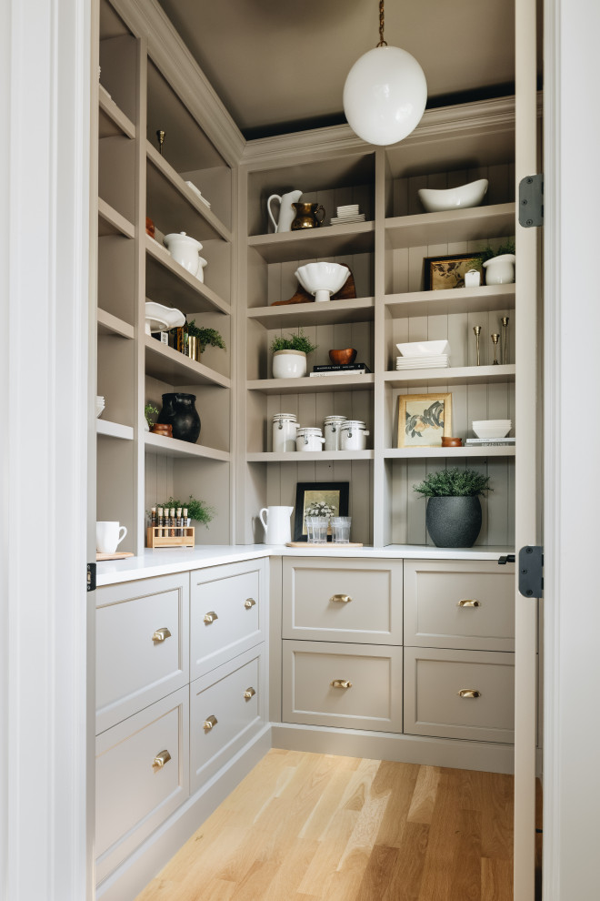 Transitional l-shaped kitchen pantry in Chicago with shaker cabinets, grey cabinets, no island, white benchtop, medium hardwood floors and brown floor.