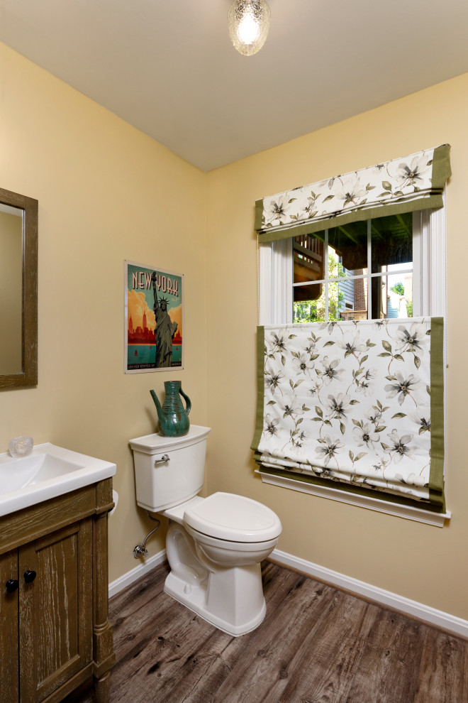 Exemple d'un WC et toilettes chic en bois brun avec un placard avec porte à panneau encastré, WC séparés, un mur jaune, sol en stratifié, un plan de toilette en quartz modifié, un sol gris, un plan de toilette blanc et meuble-lavabo sur pied.