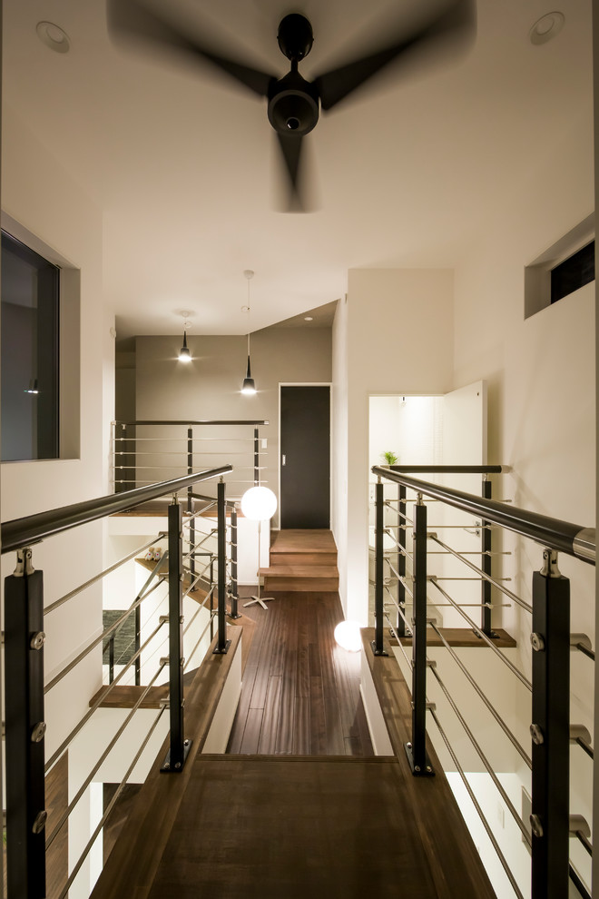 Modern hallway in Other with white walls, dark hardwood floors and brown floor.