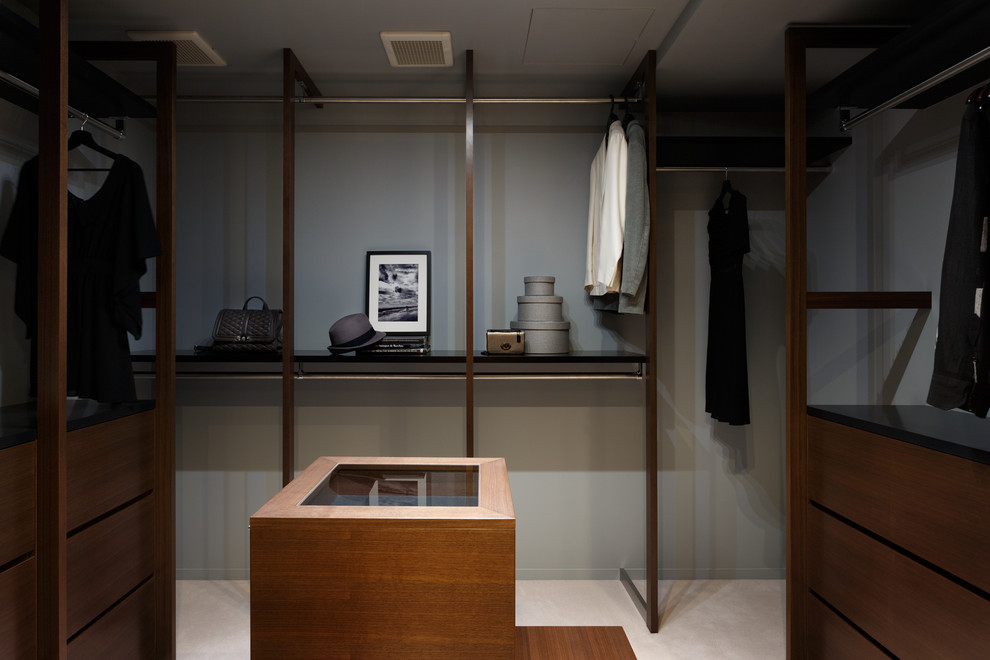 Photo of a mid-sized contemporary gender-neutral walk-in wardrobe in Tokyo Suburbs with flat-panel cabinets, dark wood cabinets and carpet.