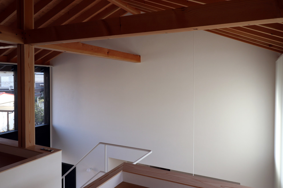 Kleines Arbeitszimmer ohne Kamin mit Arbeitsplatz, weißer Wandfarbe, hellem Holzboden, Einbau-Schreibtisch, weißem Boden, freigelegten Dachbalken und Holzdielenwänden in Sonstige