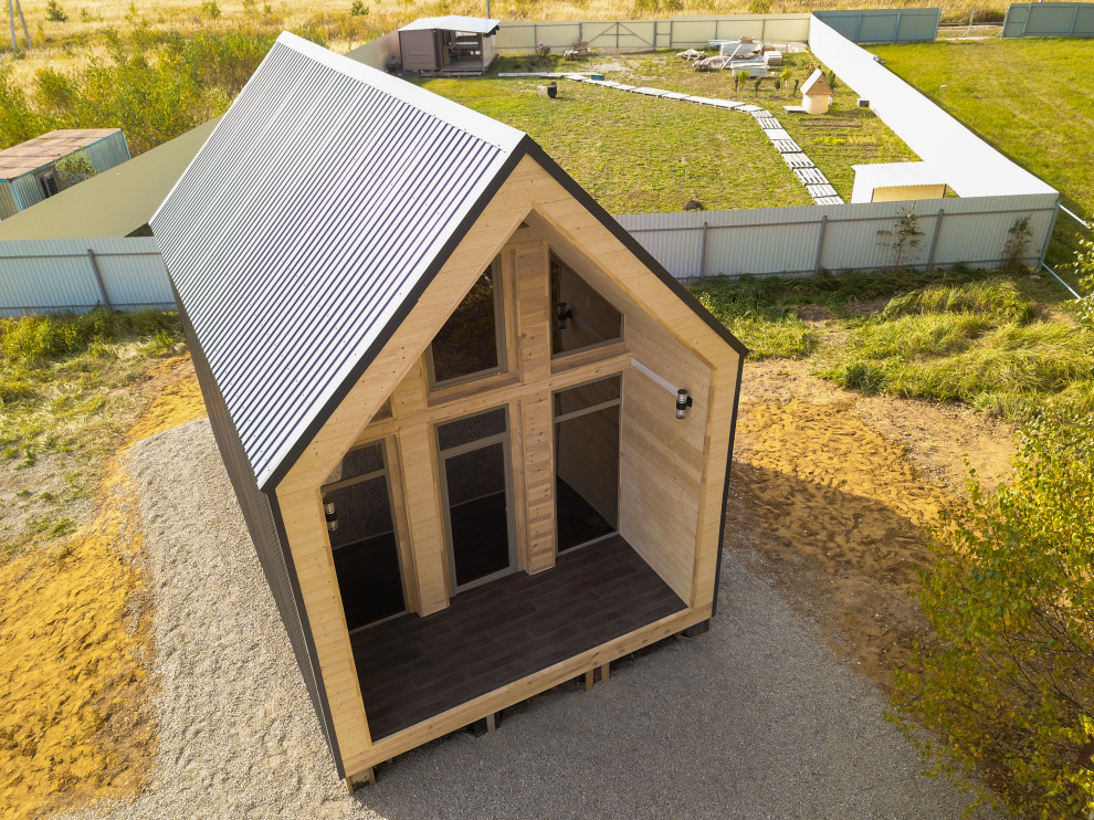 Стильный дизайн: маленький, одноэтажный, синий мини дом в современном стиле с облицовкой из металла, двускатной крышей и синей крышей для на участке и в саду - последний тренд