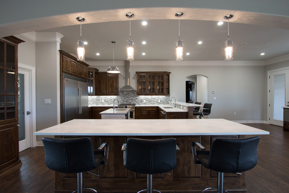 Large transitional u-shaped porcelain tile eat-in kitchen photo in Dallas with an undermount sink, raised-panel cabinets, medium tone wood cabinets, quartz countertops, gray backsplash, mosaic tile backsplash, stainless steel appliances and two islands