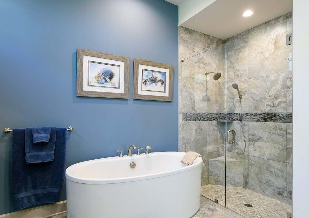 This is an example of a mid-sized beach style master bathroom in Jacksonville with a freestanding tub, an alcove shower, gray tile, glass sheet wall, blue walls, ceramic floors, grey floor and a hinged shower door.