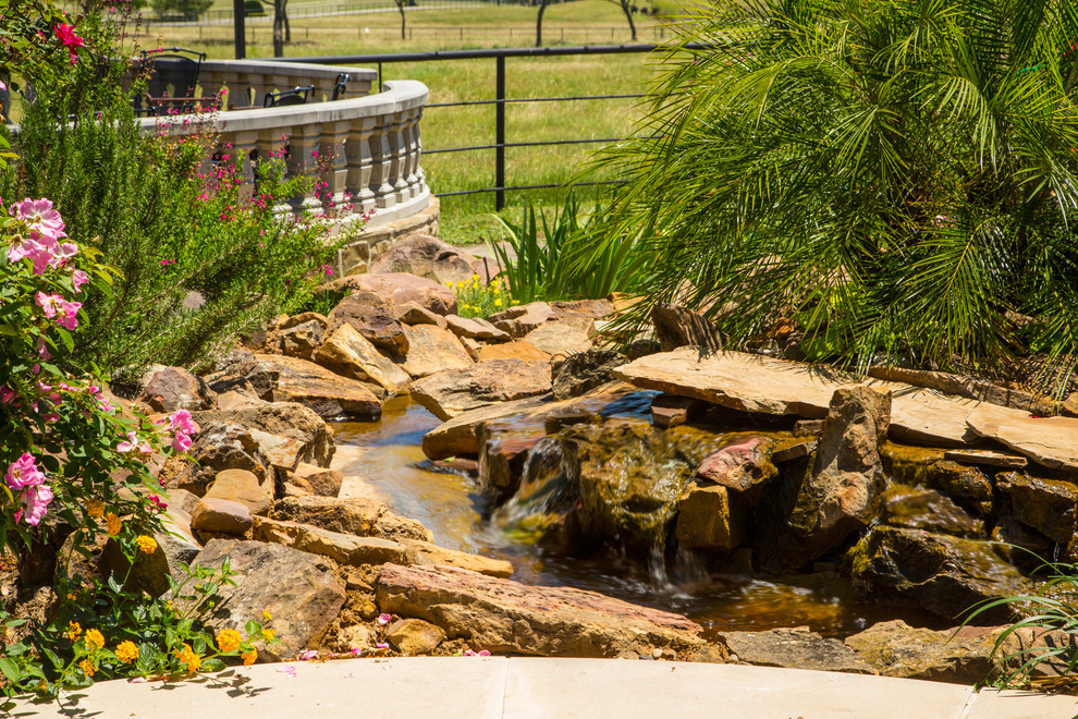 Design ideas for a large country backyard full sun xeriscape in Dallas with with pond and natural stone pavers.