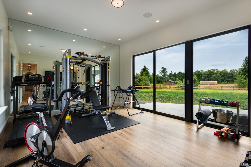 Large transitional home weight room in Vancouver with white walls, medium hardwood floors and brown floor.