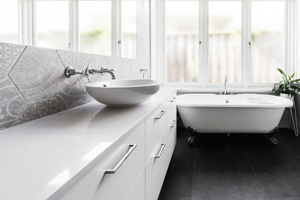 Photo of a mid-sized contemporary master bathroom in Melbourne with flat-panel cabinets, white cabinets, a claw-foot tub, an open shower, a one-piece toilet, gray tile, ceramic tile, grey walls, ceramic floors, a vessel sink, engineered quartz benchtops, grey floor and a hinged shower door.