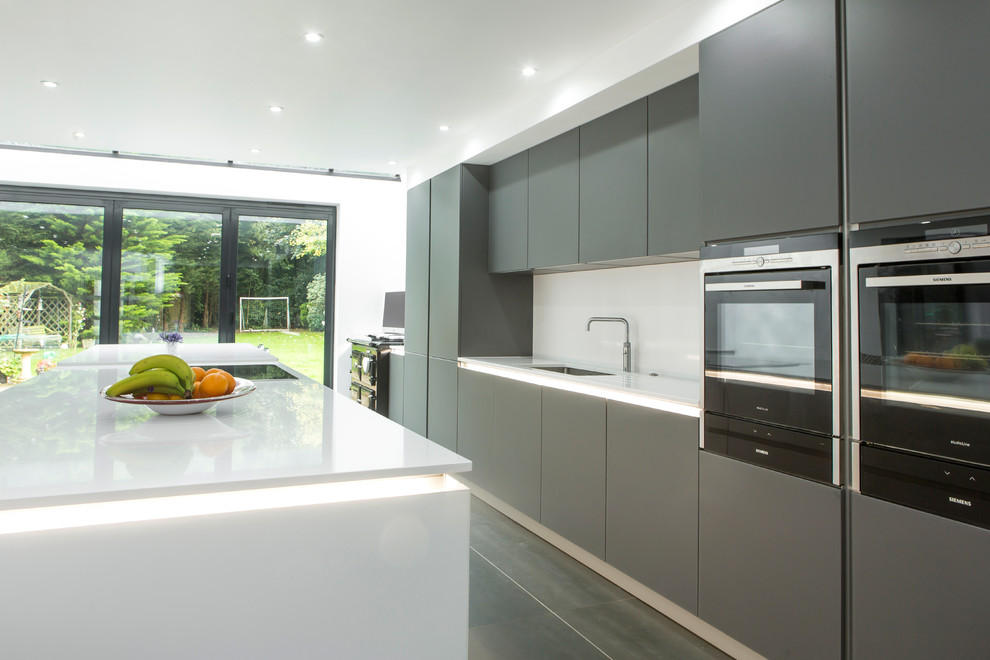 Large contemporary single-wall open plan kitchen in Essex with an integrated sink, flat-panel cabinets, grey cabinets, quartzite benchtops, white splashback, stone slab splashback, stainless steel appliances, porcelain floors and with island.