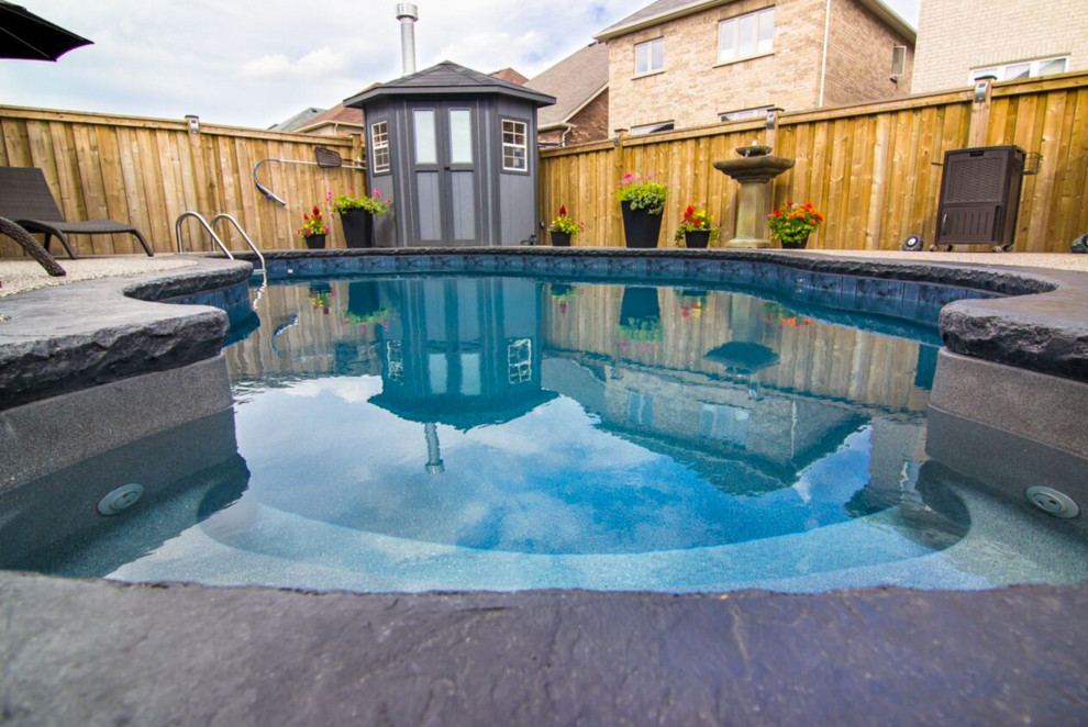 Example of a small transitional backyard stamped concrete and kidney-shaped pool design in Toronto