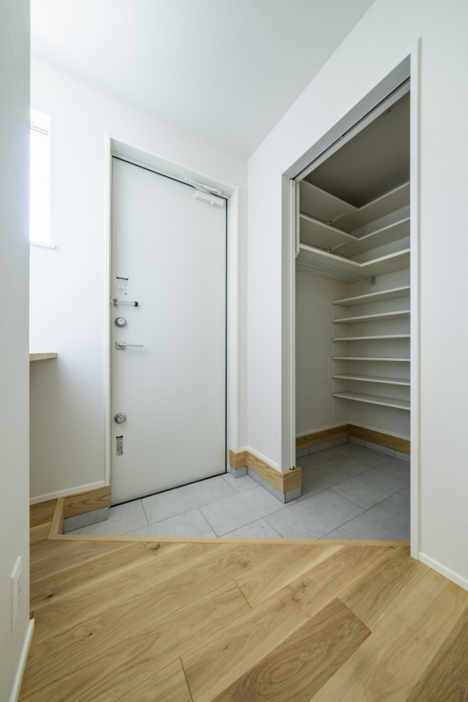 Ejemplo de hall blanco moderno de tamaño medio con paredes blancas, suelo de madera clara, suelo marrón, papel pintado, puerta simple, puerta blanca y papel pintado