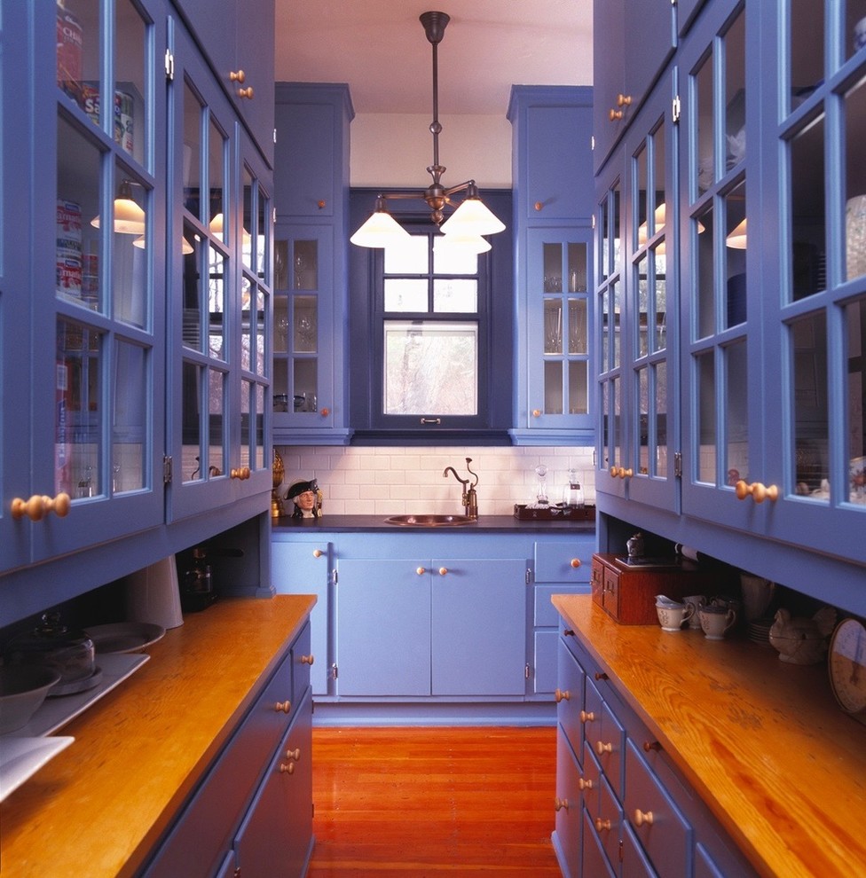 Example of a large transitional galley medium tone wood floor and brown floor eat-in kitchen design in Boise with a drop-in sink, glass-front cabinets, blue cabinets, wood countertops, white backsplash, subway tile backsplash, stainless steel appliances and no island