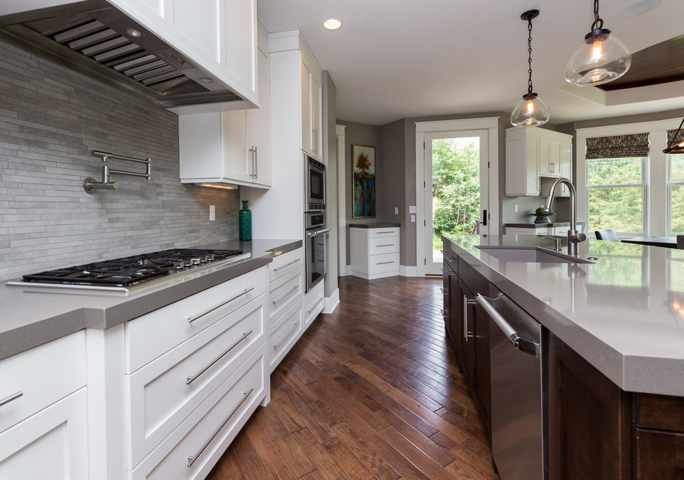 Inspiration for a large transitional l-shaped dark wood floor eat-in kitchen remodel with an undermount sink, shaker cabinets, white cabinets, solid surface countertops, gray backsplash, stainless steel appliances and an island