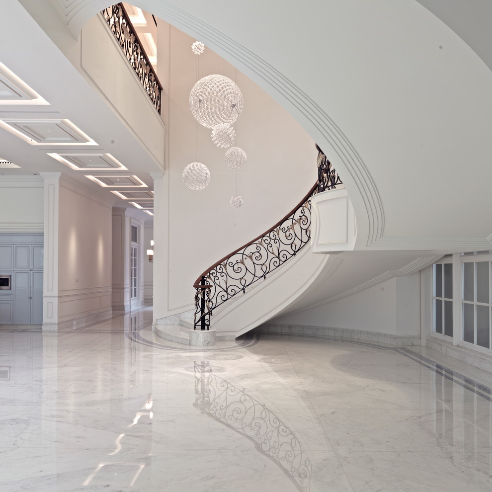 Large traditional marble curved staircase in Portland with limestone risers and metal railing.