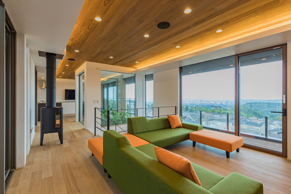 Immagine di un soggiorno minimalista di medie dimensioni e aperto con pareti bianche, pavimento in legno massello medio, stufa a legna, TV a parete e pavimento marrone