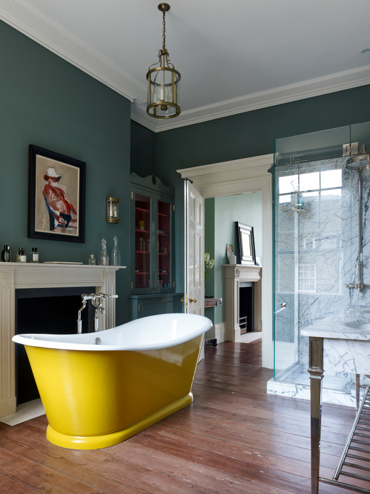 Mid-sized traditional master bathroom in London with a freestanding tub, a corner shower, a hinged shower door, white tile, marble, green walls, medium hardwood floors and brown floor.