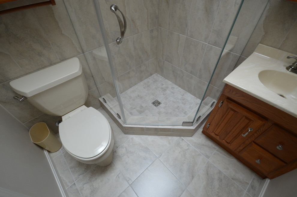 Photo of a small arts and crafts bathroom in Baltimore with an integrated sink, raised-panel cabinets, medium wood cabinets, grey walls and porcelain floors.