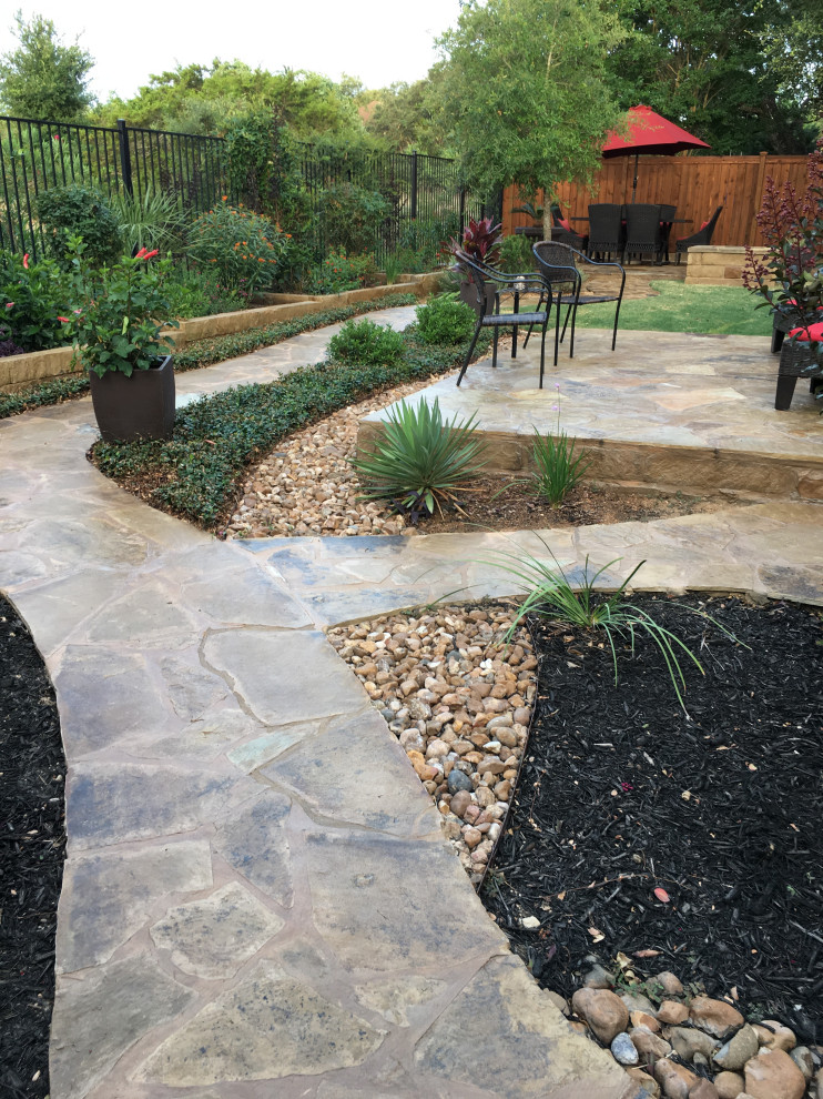 Inspiration for a large backyard full sun formal garden for spring in Austin with a garden path and river rock.