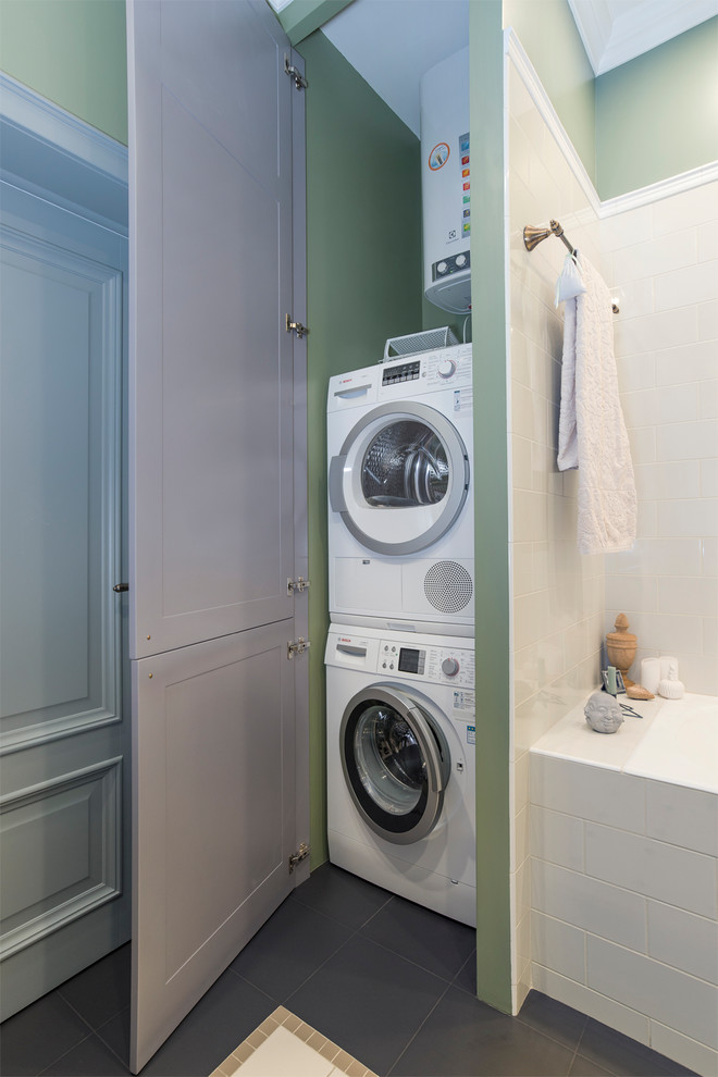 This is an example of a transitional laundry room in Moscow with green walls and a stacked washer and dryer.