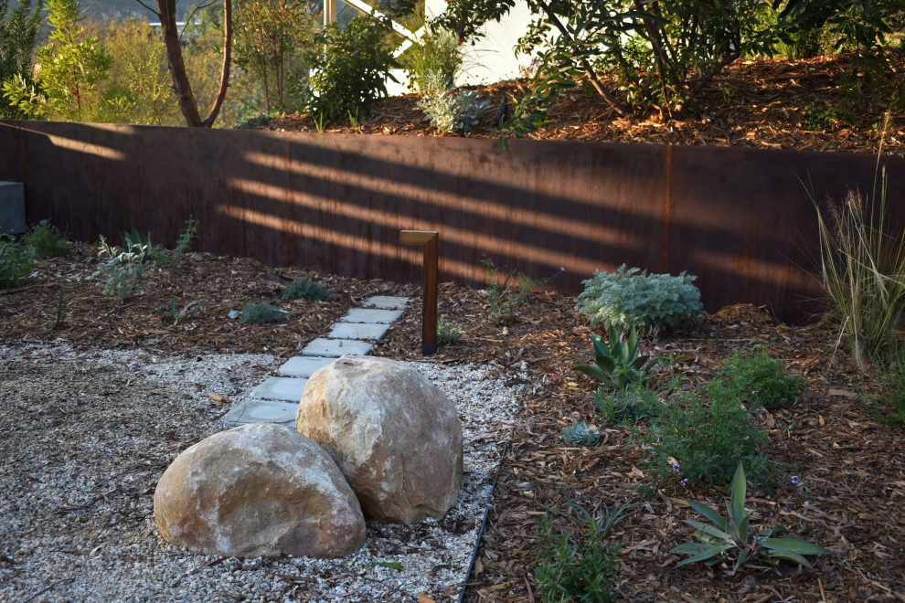 This is an example of a large modern drought-tolerant and full sun backyard concrete paver and metal fence flower bed in Los Angeles for spring.
