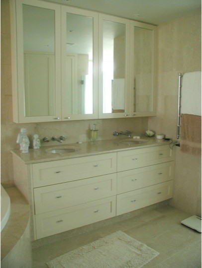 This is an example of a small eclectic master bathroom in Sydney with an undermount sink, recessed-panel cabinets, beige cabinets, marble benchtops, a corner tub, a one-piece toilet, beige tile, stone tile, beige walls and marble floors.