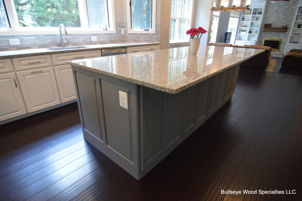 Example of a large transitional u-shaped dark wood floor and brown floor eat-in kitchen design in DC Metro with an undermount sink, raised-panel cabinets, white cabinets, granite countertops, gray backsplash, glass tile backsplash, stainless steel appliances and an island