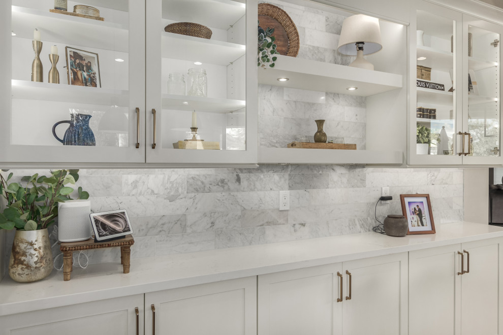Inspiration for a mid-sized transitional u-shaped porcelain tile and brown floor enclosed kitchen remodel in Phoenix with a farmhouse sink, shaker cabinets, white cabinets, quartz countertops, white backsplash, marble backsplash, stainless steel appliances, an island and white countertops