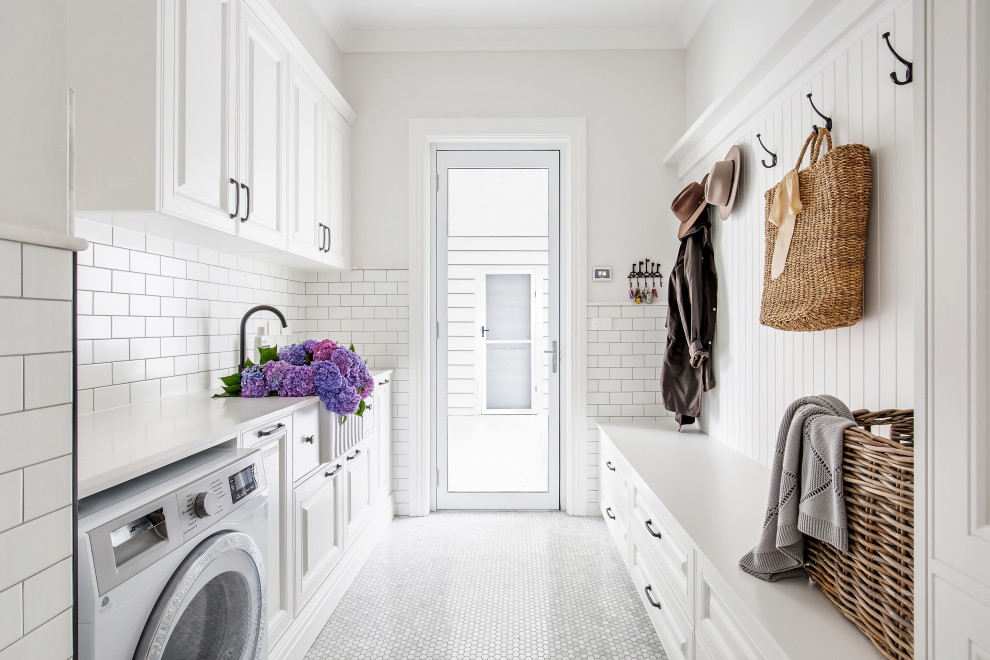 Design ideas for a country laundry room in Other with a farmhouse sink, white cabinets, white splashback, grey floor and white benchtop.