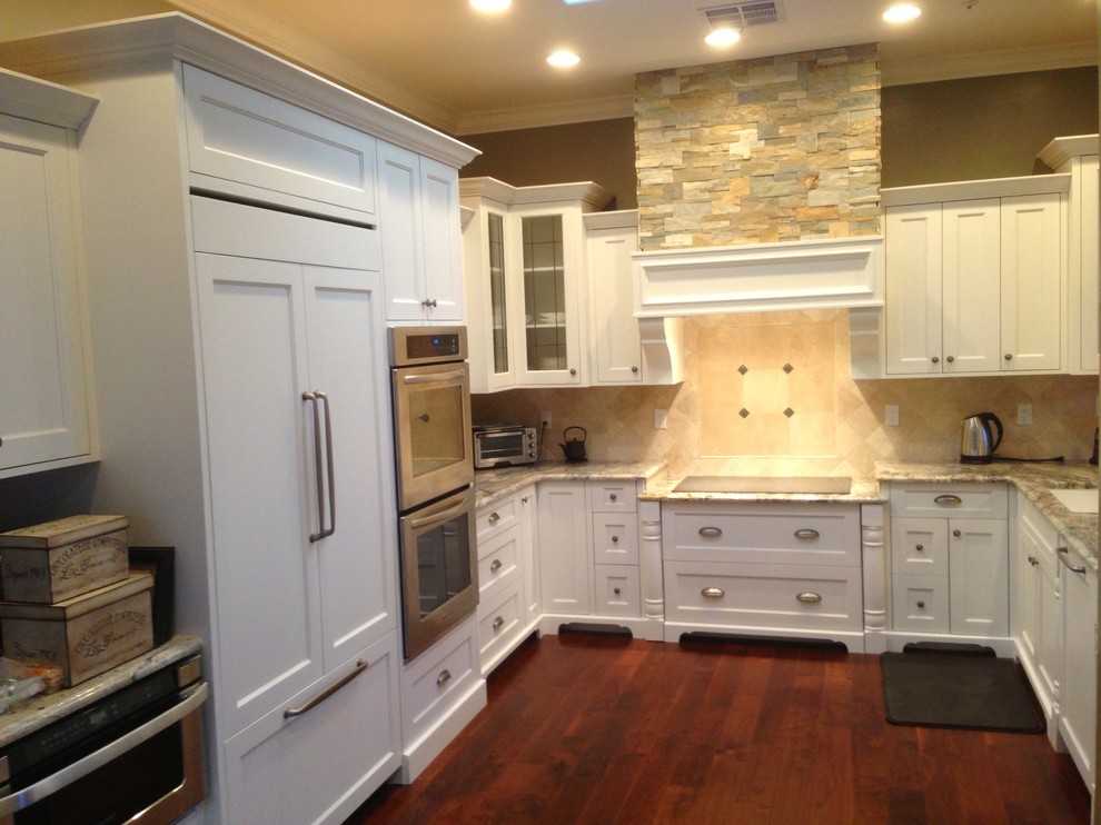 Inspiration for a mid-sized transitional u-shaped dark wood floor and brown floor enclosed kitchen remodel in Phoenix with an undermount sink, shaker cabinets, white cabinets, granite countertops, brown backsplash, paneled appliances, no island, brown countertops and travertine backsplash