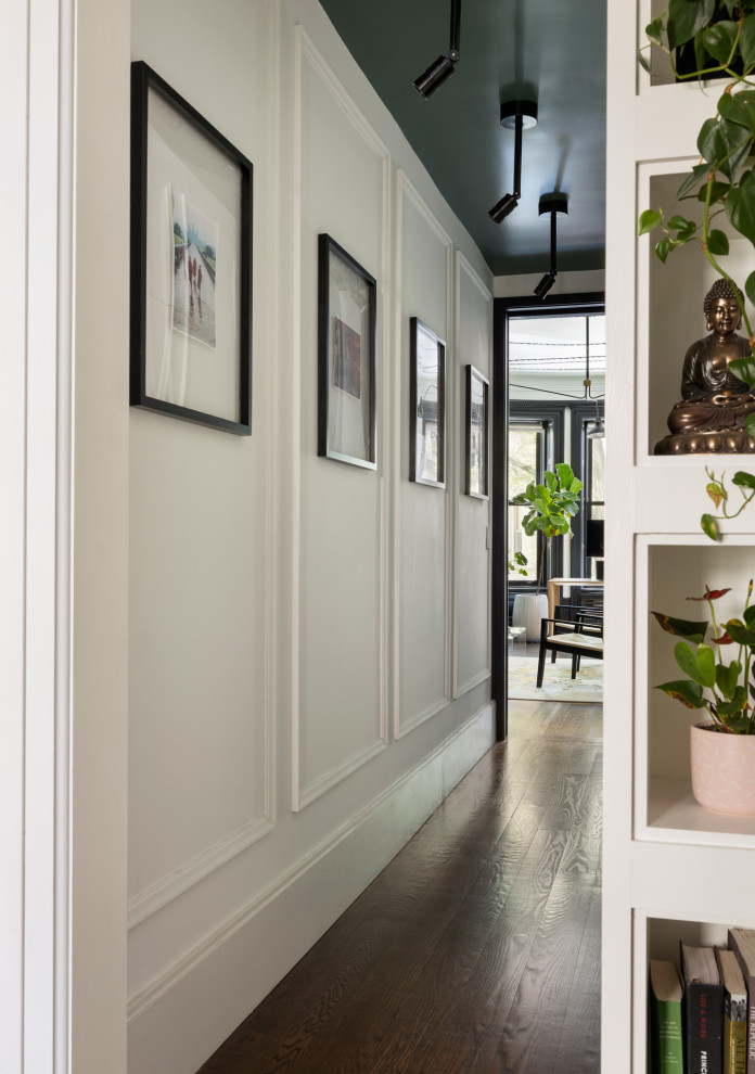 Small transitional hallway in New York with white walls, dark hardwood floors, brown floor and wood walls.