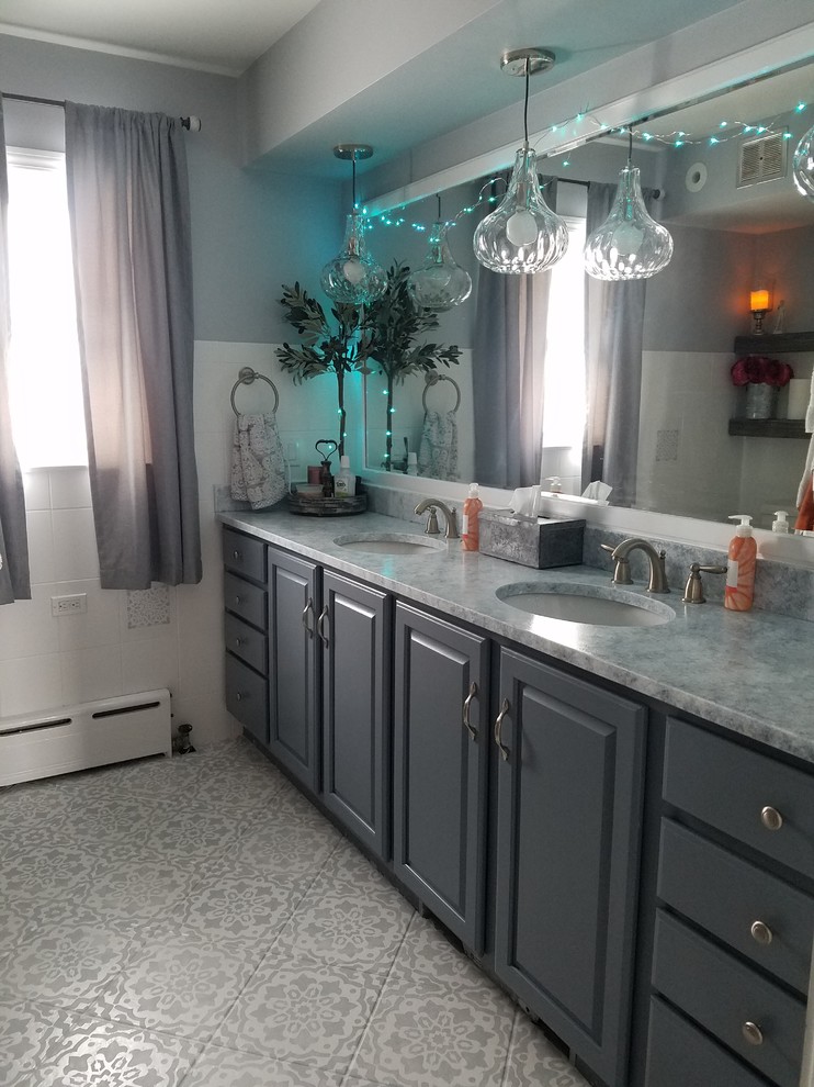 Photo of a small traditional master bathroom in Chicago with furniture-like cabinets, blue cabinets, a drop-in tub, a shower/bathtub combo, a one-piece toilet, white tile, ceramic tile, white walls, ceramic floors, an undermount sink, granite benchtops, multi-coloured floor, a shower curtain and white benchtops.