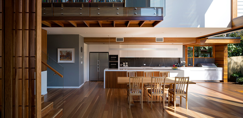 Photo of a contemporary dining room in Brisbane with white walls, light hardwood floors, a ribbon fireplace and a stone fireplace surround.