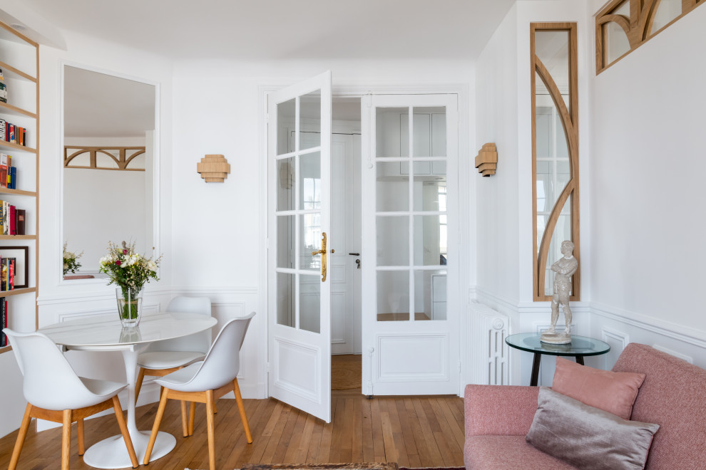 Стильный дизайн: гостиная комната среднего размера, в белых тонах с отделкой деревом в скандинавском стиле с с книжными шкафами и полками, белыми стенами, светлым паркетным полом и панелями на стенах - последний тренд