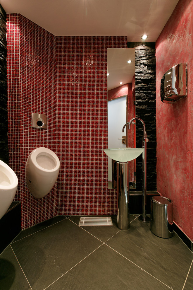 Réalisation d'un très grand WC suspendu asiatique avec un carrelage rouge, un carrelage en pâte de verre, un mur noir, un sol en ardoise, un plan vasque, un plan de toilette en verre, un sol noir, meuble-lavabo sur pied et un plafond décaissé.