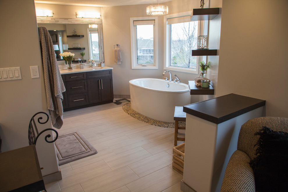 Example of a large transitional master beige tile and glass sheet porcelain tile freestanding bathtub design in Edmonton with shaker cabinets, brown cabinets, a two-piece toilet, beige walls, an undermount sink and quartz countertops