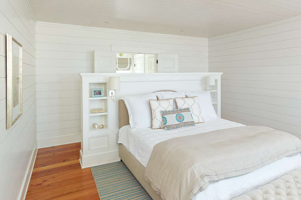 Tropical guest bedroom in Charleston with white walls, medium hardwood floors and no fireplace.