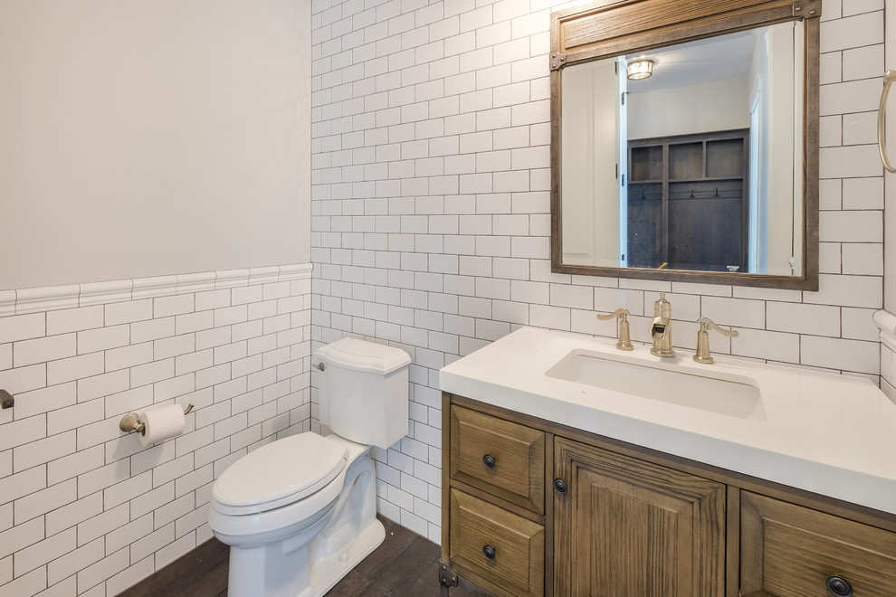 Photo of a mid-sized country powder room in Denver with raised-panel cabinets, a two-piece toilet, white tile, subway tile, white walls, dark hardwood floors, an undermount sink, quartzite benchtops, light wood cabinets and white benchtops.