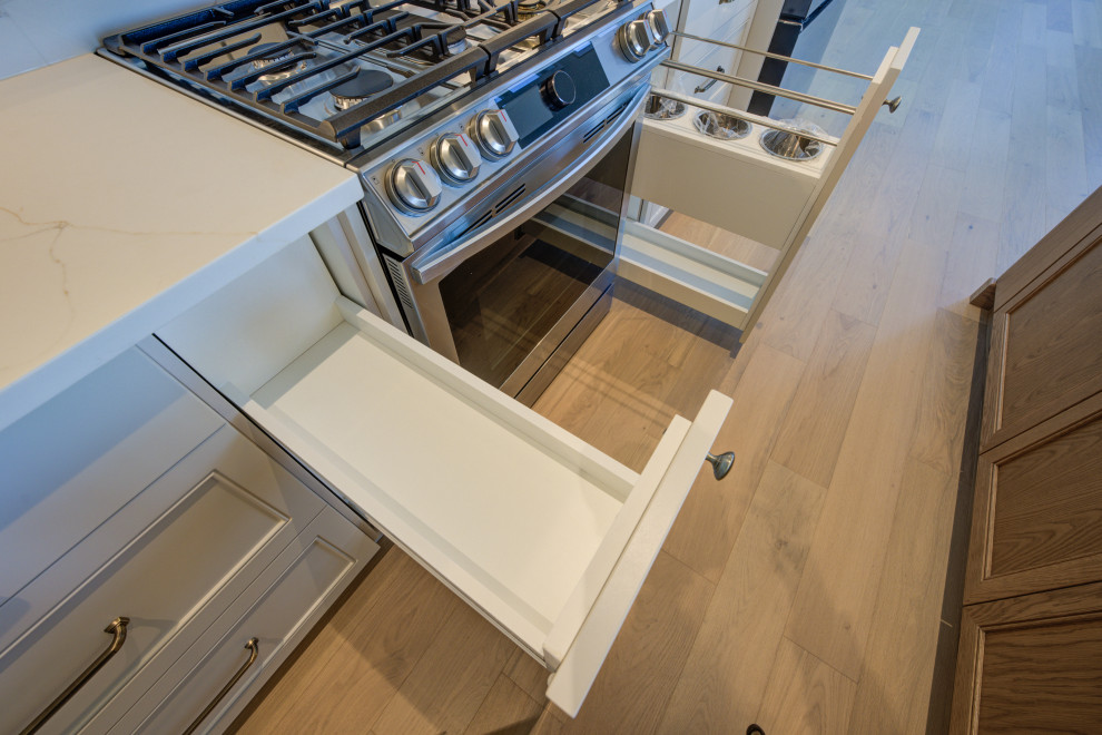 Inspiration for a mid-sized transitional single-wall light wood floor open concept kitchen remodel in Toronto with an undermount sink, shaker cabinets, white cabinets, quartz countertops, white backsplash, quartz backsplash, stainless steel appliances, an island and white countertops