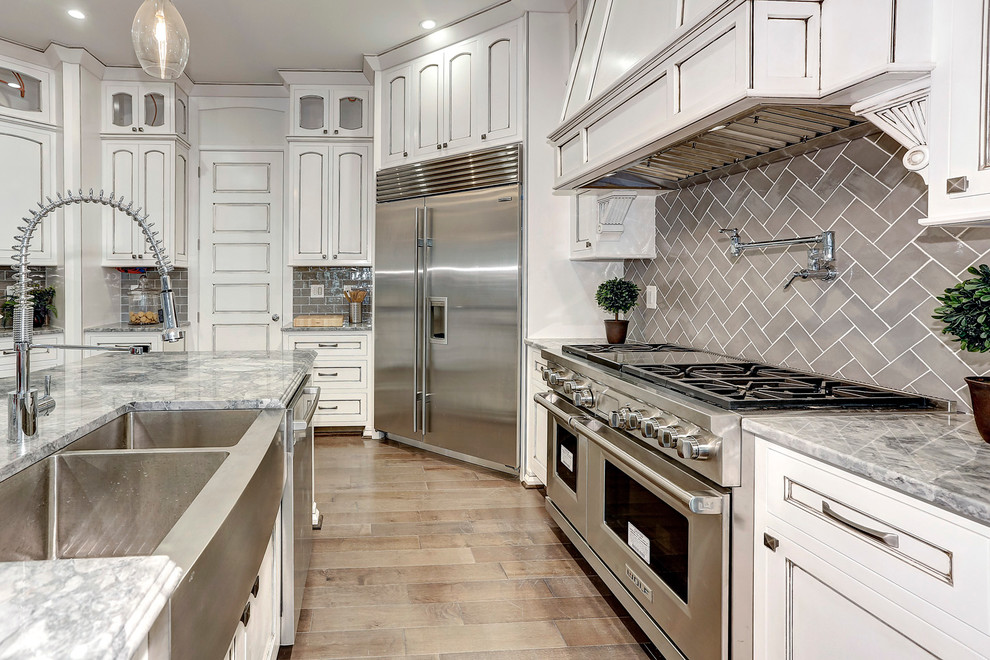 Design ideas for a large traditional u-shaped eat-in kitchen in DC Metro with an undermount sink, recessed-panel cabinets, white cabinets, granite benchtops, subway tile splashback, stainless steel appliances, medium hardwood floors, with island and brown splashback.