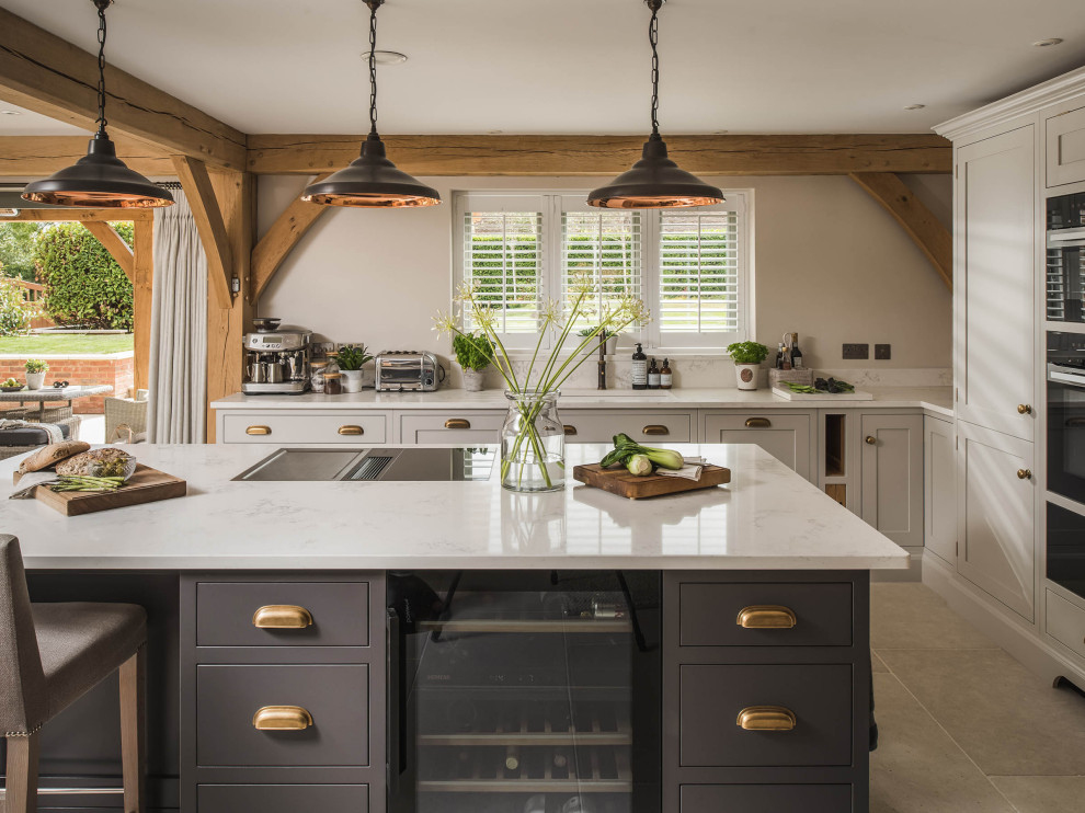 Offene Landhaus Küche mit Unterbauwaschbecken, Schrankfronten mit vertiefter Füllung, schwarzen Elektrogeräten, Kücheninsel und weißer Arbeitsplatte in Essex