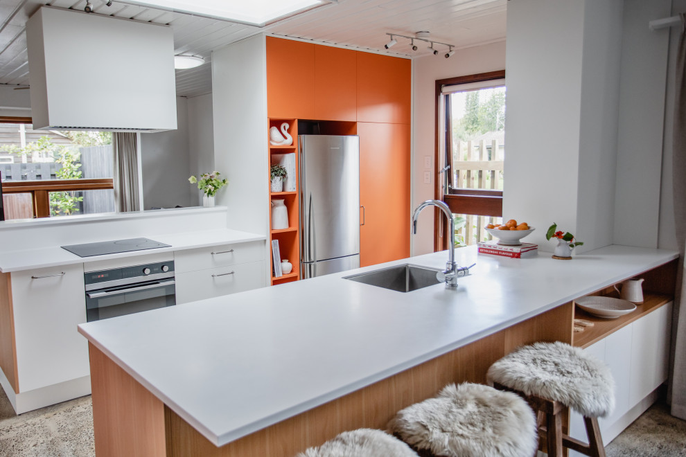 Retro inredning av ett mellanstort vit vitt kök, med en enkel diskho, släta luckor, orange skåp, bänkskiva i koppar, rostfria vitvaror, betonggolv, en halv köksö och grått golv