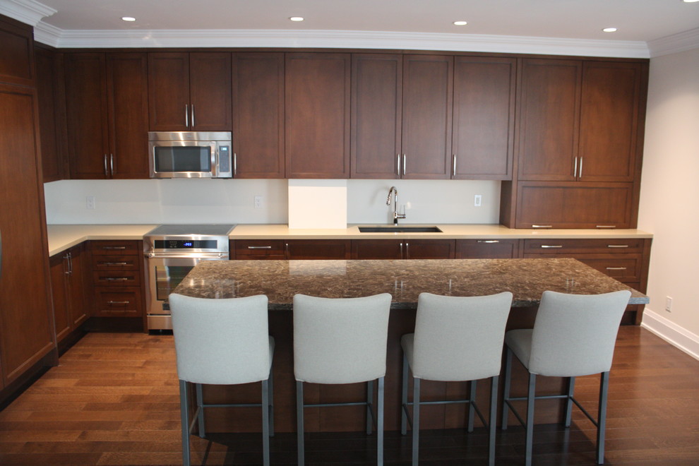 Mid-sized traditional l-shaped eat-in kitchen in Toronto with an undermount sink, shaker cabinets, medium wood cabinets, quartz benchtops, brown splashback, glass sheet splashback, stainless steel appliances, medium hardwood floors and with island.