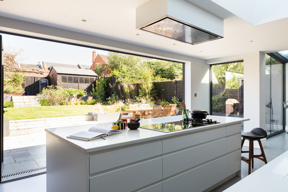 Photo of a contemporary kitchen in London with concrete floors, flat-panel cabinets, white cabinets and with island.