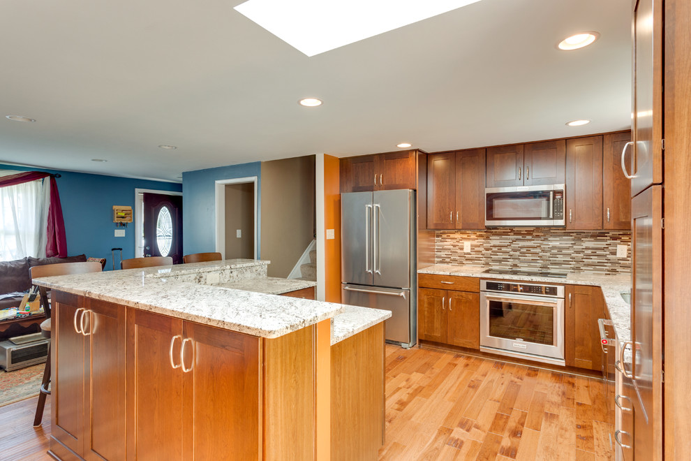 Mid-sized transitional eat-in kitchen in DC Metro with an undermount sink, shaker cabinets, granite benchtops, mosaic tile splashback, stainless steel appliances and with island.