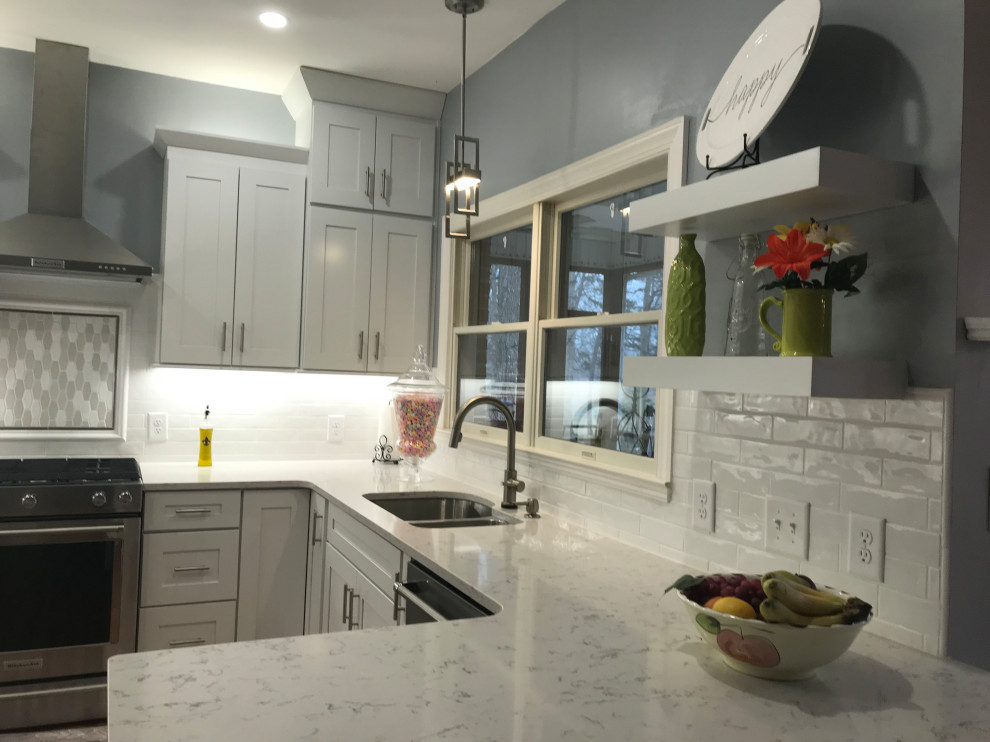 Kitchen - mid-sized transitional u-shaped medium tone wood floor kitchen idea in Charlotte with an undermount sink, shaker cabinets, white cabinets, quartz countertops, white backsplash, subway tile backsplash, stainless steel appliances and a peninsula